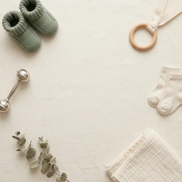 Soft nursery flat lay with baby items in warm cream tones